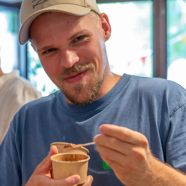 Gast mit Kappe hält einen Eisbecher